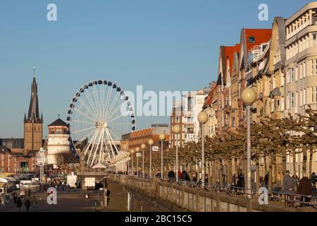 Deutschland, Nordrhein-Westfalen, Düsseldorf, Lichterkette entlang der Uferpromenade mit Riesenrad und St. Lambertus-Kirche im Hintergrund Stockfoto