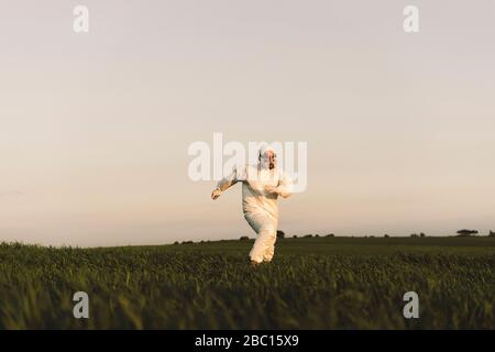 Mann mit Schutzanzug und Maske läuft auf dem Land Stockfoto