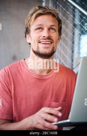 Porträt eines jungen Mannes mit T-Shirt mit Laptop Stockfoto