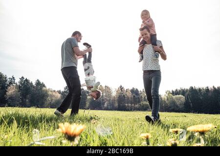 Glückliche Familie mit zwei Kindern, die im Frühling auf einer Wiese Spaß haben Stockfoto