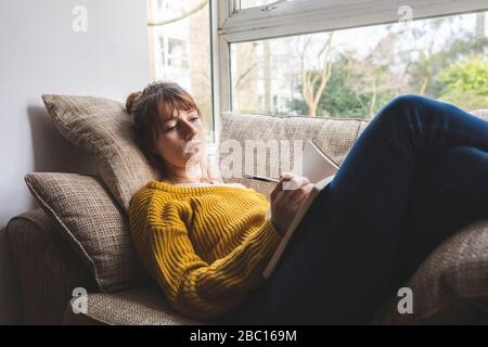 Porträt einer Frau auf der Couch liegend Zeichnung in Skizzenbuch Stockfoto