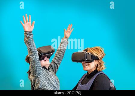 Mutter und ihre Tochter spielen mit virtuellen Reality-Gläsern, Mutter und Tochter, die Spaß mit virtuellen Reality-Headsets haben, isoliert auf acquamarine Stockfoto