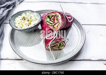 Rote Bete Wraps gefüllt mit Schinken, Käse, Mais, Eisbergsalat, Gurken und Frischkäse Stockfoto