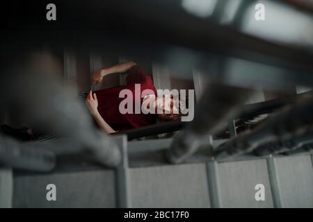 Porträt eines ernsten jungen Mannes, der auf einer Treppe sitzt und nach oben schaut Stockfoto