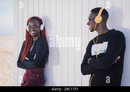 Porträt von glücklichen Teenager-Mädchen und junger Mann mit Kopfhörern im Freien Stockfoto