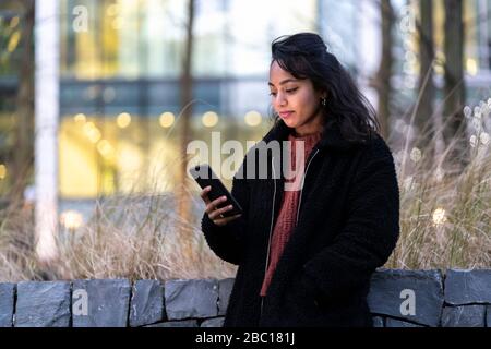 Junge Frau mit Handy in der Stadt Stockfoto