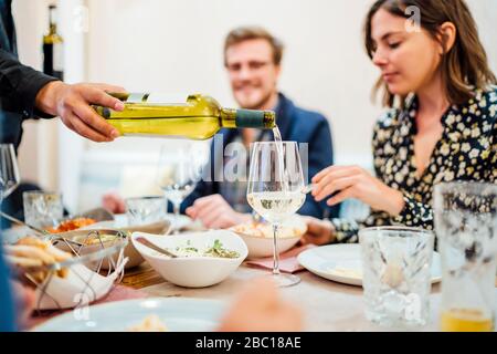 Freunde essen in einem indischen Restaurant, Kellner gießt Wein in Gläser Stockfoto