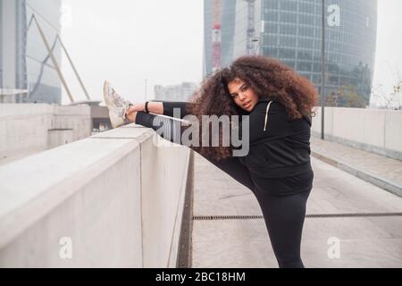 Plus Größe sportliche junge Frau Stretching in der Stadt Stockfoto