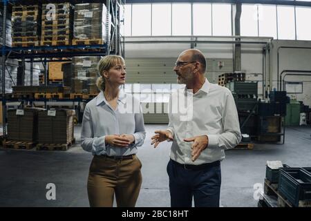 Mann und Frau gehen und reden in einer Fabrik Stockfoto