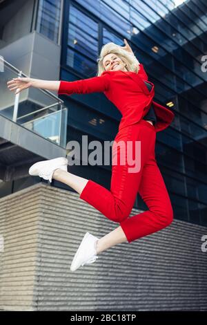 Blonde Geschäftsfrau trägt roten Anzug Stockfoto