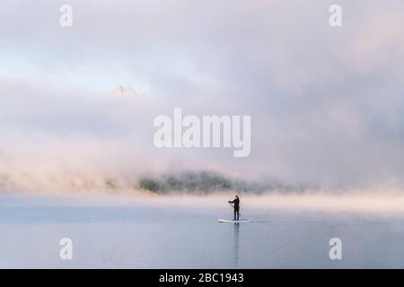 Frau steht auf Paddelsurfen auf einem See Stockfoto