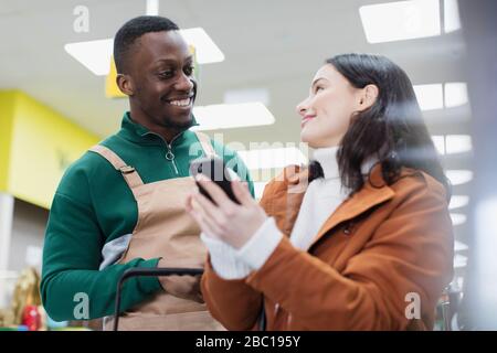 Lebensmittelhändler helfen Kunden mit Smartphone im Supermarkt Stockfoto