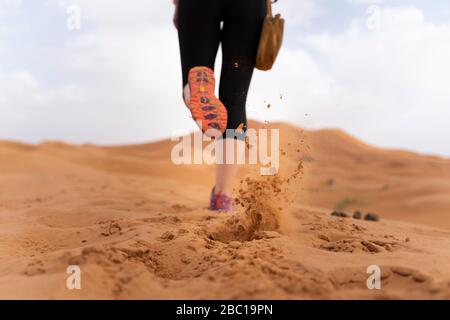 Füße einer Frau, die auf Sanddüne in der Sahara, Merzouga, Marokko läuft Stockfoto