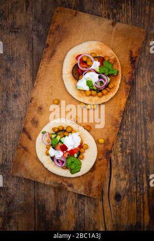 Israelischer Sabich mit Pita-Brot, Auberginen, Kichererbsen, Tomaten, Gurke, Joghurt und Zhoug-Sauce Stockfoto