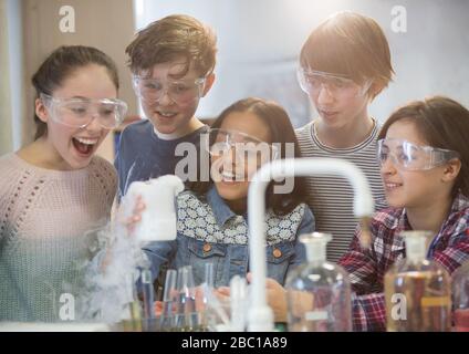 Überraschte Studenten, die wissenschaftliche Experimente durchführen und dabei chemische Reaktionen im Klassenraum-Labor beobachten Stockfoto