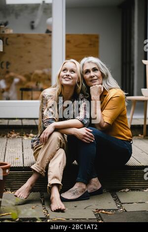 Lächelnde Mutter und Erwachsene Tochter sitzen auf der Terrasse Stockfoto