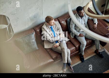 Zwei Geschäftsleute sitzen auf der Couch in der Hotellobby Stockfoto