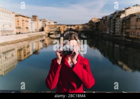 Junge Frau, die ein Foto auf einer Brücke über dem Fluss Arno, Florenz, Italien macht Stockfoto