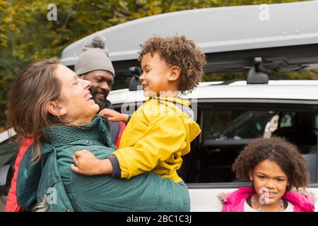 Fröhliche Familie umarmt auf dem Parkplatz vor dem Auto Stockfoto