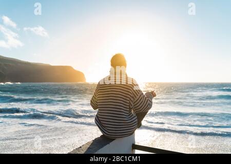 Mann meditiert an der Küste bei Sonnenuntergang, Sao Miguel Insel, Azoren, Portugal Stockfoto