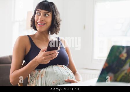 Glückliche schwangere Frau mit Smartphone Stockfoto