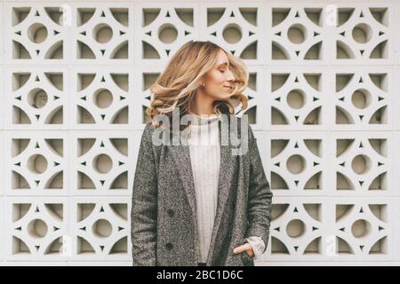 Unbeschwerte blonde Frau im grauen Mantel Stockfoto