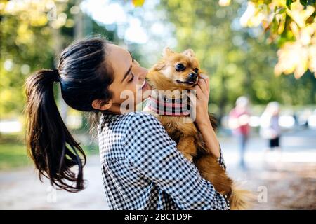 Glückliche junge Frau, die Hund in einem Park hält Stockfoto