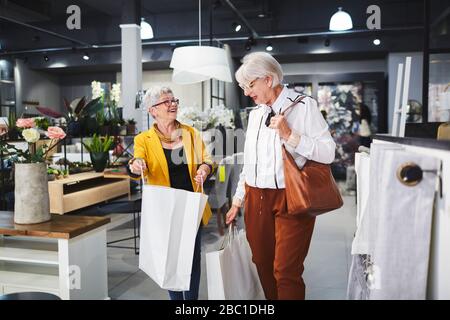 Seniorinnen Freunde verlassen Hauswarenladen mit Einkaufstaschen Stockfoto