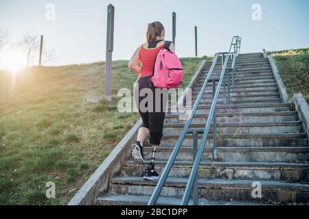 Sportliche junge Frau mit Beinprothese beim Treppensteigen Stockfoto