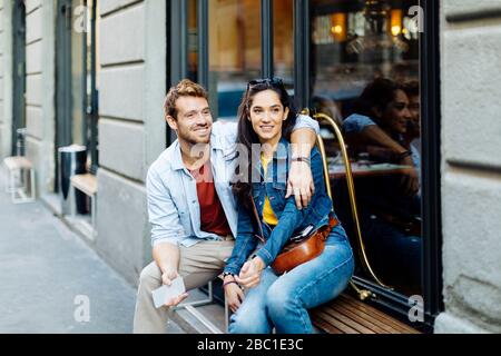 Fröhliches junges Paar auf Fensterbank in der Stadt, Mailand, Italien Stockfoto