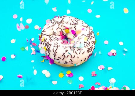Donut Puderschokolade Strohhalme blauer bunt gefärbter Konfettihintergrund. Feiertagsfeier-Konzept. Stockfoto