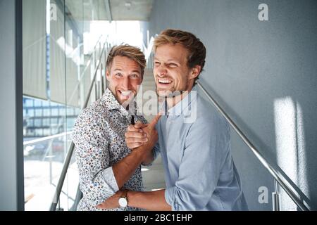 Porträt von zwei glücklichen jungen Geschäftsleuten, die sich die Hände schütteln Stockfoto