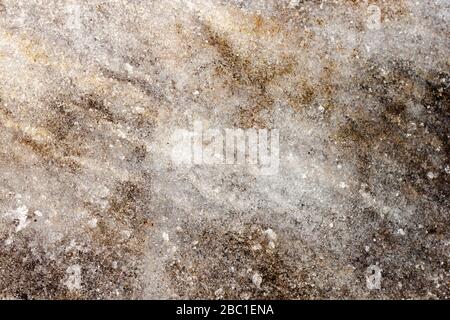 Frühe Frühjahrszeit schmutziger grau geschmolzener Schnee mit Sandmuster Textur Nahaufnahme Grunge Hintergrund. Stockfoto
