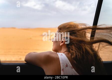 Junge Frau im Auto, die sich aus dem Fenster in der Sahara-Wüste, Merzouga, Marokko lehnt Stockfoto