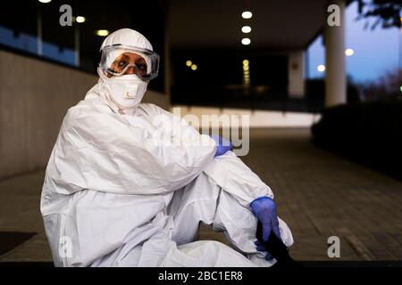 Wissenschaftlerin mit Schutzanzug und Maske vor einem Labor Stockfoto