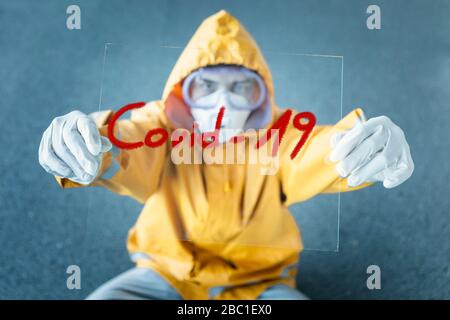 Porträt eines Mannes mit Schutzkleidung und Schild 'Covid 19' Stockfoto