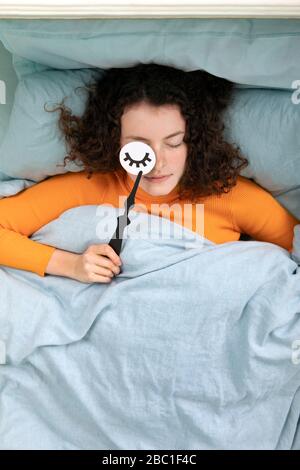 Porträt einer schlafenden jungen Frau im Bett mit Papiermaske Stockfoto