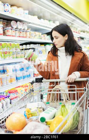 Frau liest Etikett auf Container im Supermarkt Stockfoto