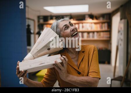 Glückliche grauhaarige Frau mit Holzgrammophon Stockfoto
