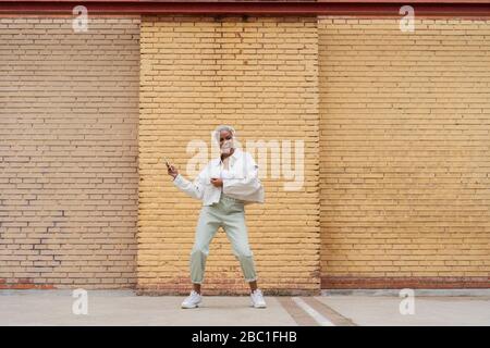 Frau, die Musik mit Kopfhörern hört und im Freien tanzt Stockfoto