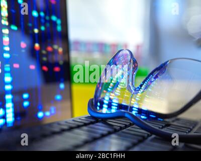 DNA-Profilergebnisse spiegeln sich in einer Schutzbrille auf der Laptop-Tastatur wider Stockfoto