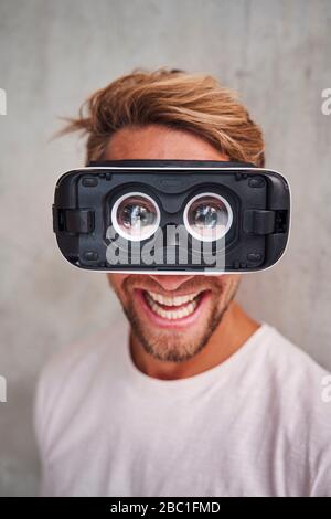Lachender junger Mann, der eine Virtual-Reality-Brille trägt Stockfoto