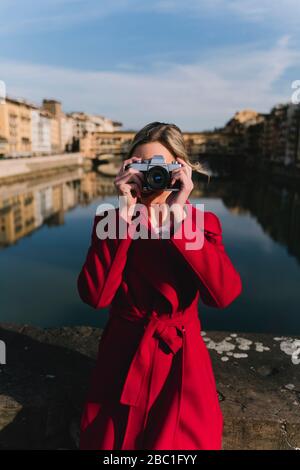 Junge Frau, die ein Foto auf einer Brücke über dem Fluss Arno, Florenz, Italien macht Stockfoto