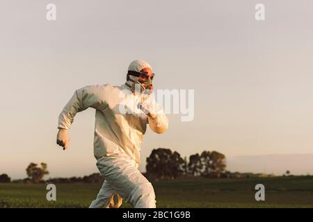 Mann mit Schutzanzug und Maske läuft auf dem Land Stockfoto