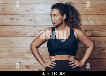 Porträt der selbstbewussten athletischen jungen Frau an der Holzwand stehend Stockfoto