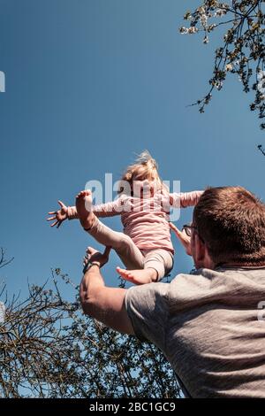 Vater wirft kleine Tochter in die Luft Stockfoto