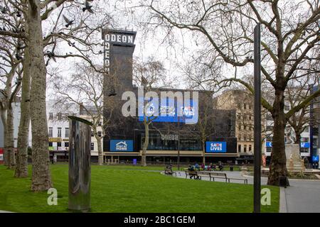 Ein fast menschenleerer Leicester Square in Central London während des Ausbruchs des Corona-Virus. Das Odeon Cinema warnt Menschen davor, Leben zu retten usw. Stockfoto
