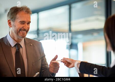 Porträt eines lächelnden Geschäftsmannes, der an der Hotelrezeption eincheckt Stockfoto