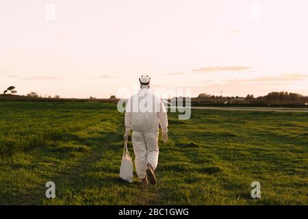 Rückansicht des Mannes mit Schutzanzug beim Wandern auf dem Land Stockfoto