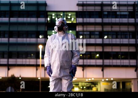 Wissenschaftlerin mit Schutzanzug und Maske vor einem Labor Stockfoto